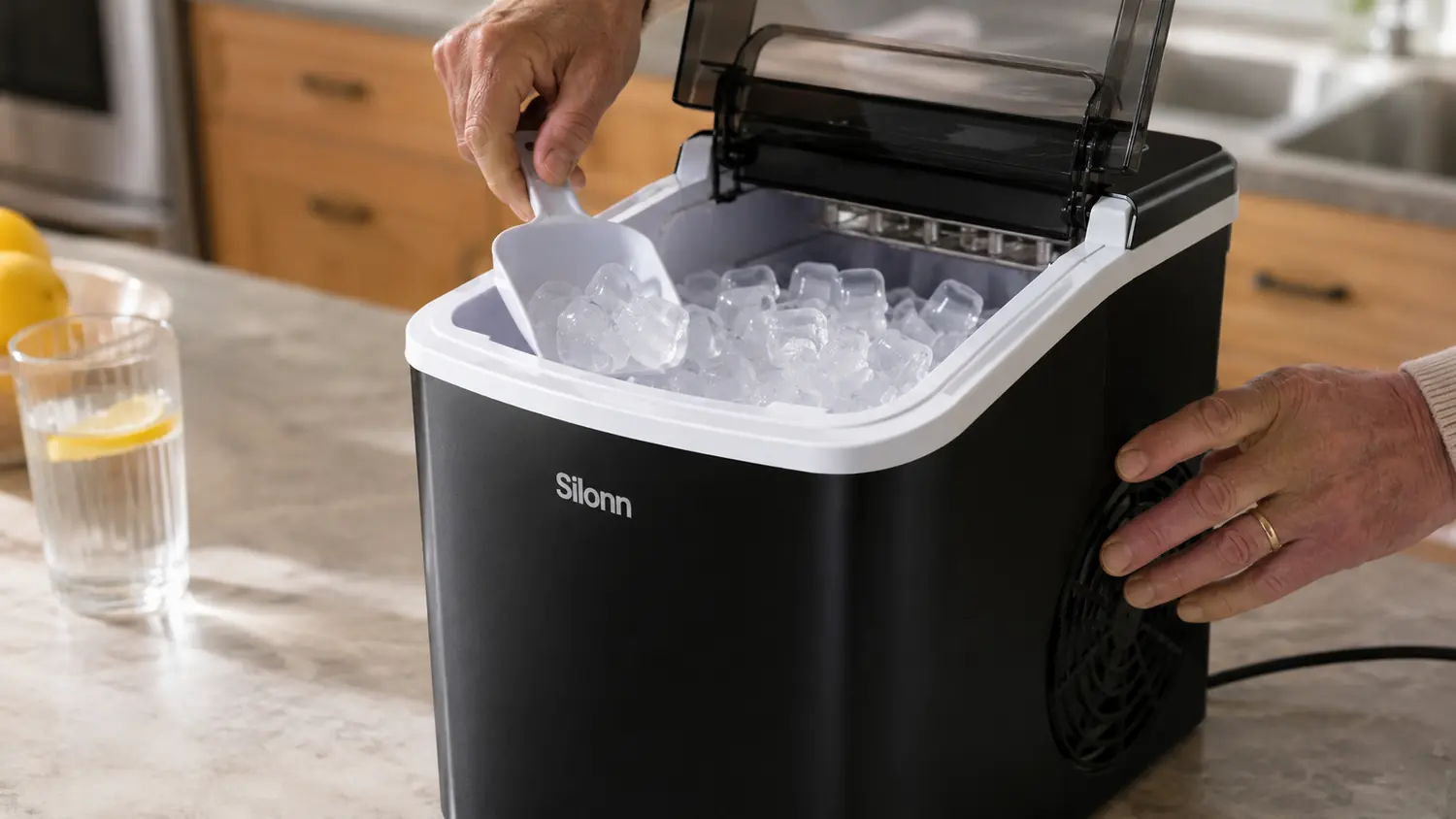Hand scooping soft chewable nugget ice from the Silonn ice maker's storage bin into a glass
